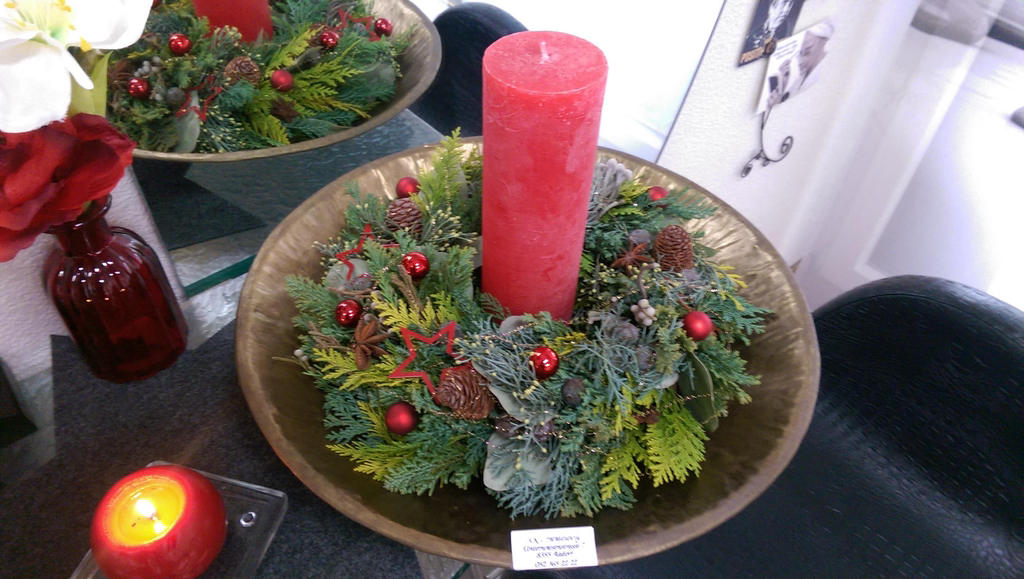 Weihnachtliches Gesteck mit roter Kerze und Kugeln in goldener Schale