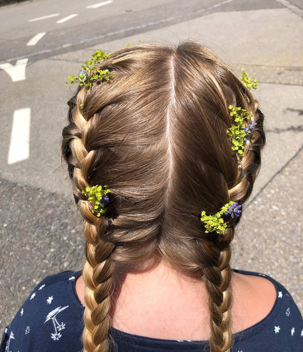 Zwei Zöpfe mit frischen Wiesenblumen